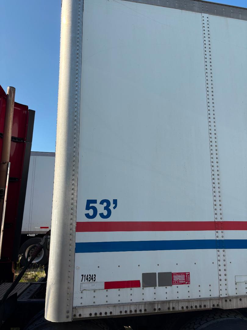 Truck trailer side with number 53' and red/blue stripes, serials and riveted metal panels.