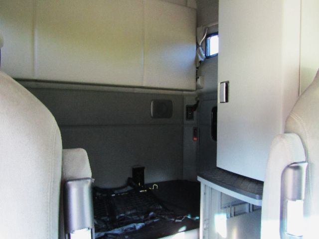 Interior of a 2020 Kenworth T680 cab showing sleeper area with white panel and side storage, front seats partially visible.
