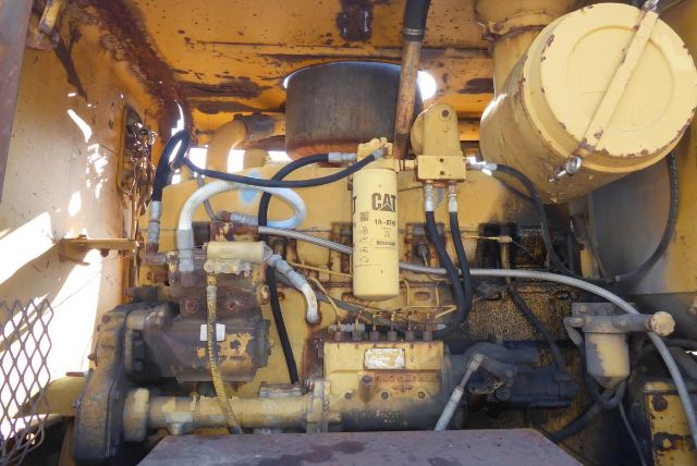 Caterpillar 16G engine bay showing Caterpillar diesel engine with yellow oil filter and hydraulic lines in service compartment
