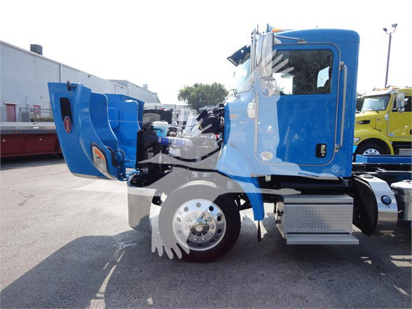 Blue Peterbilt 337 truck side view with its hood and cab tilted open. Wheel, steps, fuel tank, and chrome exhaust area visible.