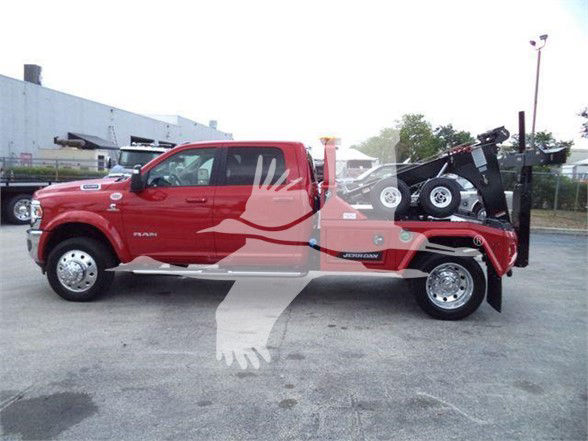 Red 2024 Ram 5500 Laramie tow truck with flatbed and wheel lifts, side view.