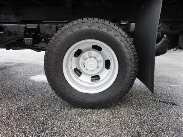 Truck wheel assembly showing steel wheel with lug nuts and rugged tire under Ram 3500 chassis.
