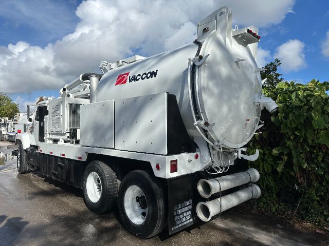 Vaccon vacuum truck rear three-quarter view showing large cylindrical storage tank, dual rear axles, exhausts, and hose compartments.