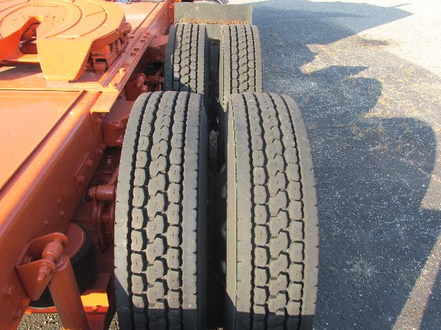Two rear dual tires on a Kenworth W900 tractor chassis with orange-colored frame and linkage.