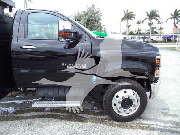 Chevrolet Silverado 6500HD truck side view showing cab and front wheel with 'Silverado 6500 HD' badge on door; dark color; background with palm trees.
