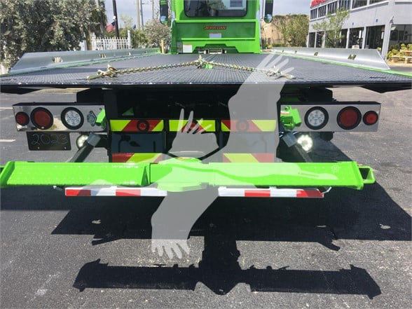 Peterbilt 337 tow truck rear view with green chassis and reflective safety markings, rear bumper and deck plate visible