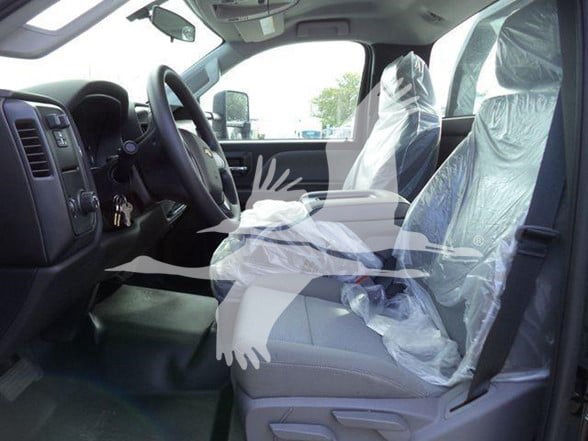 Truck interior showing front seats in plastic covers, steering wheel, dashboard; light gray seats and black dashboard.