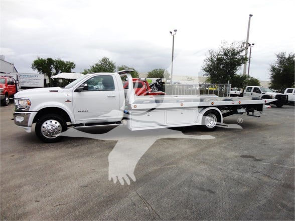 Ram 5500 HD tow truck with flatbed, white exterior, side view showing front grille and wheels.