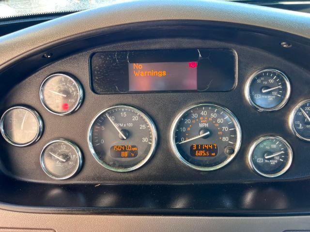 Peterbilt truck dashboard showing digital display reading No Warnings; multiple analog gauges with speeds and RPM; odometer reading 1504.1? miles; 91? The image focuses on gauge cluster with orange warning text off; center display blank.