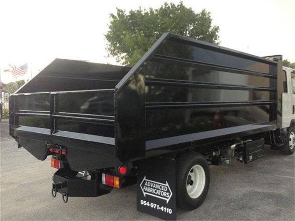 Dump body truck with black steel dump bed, side panels, rear tailgate, and Advanced Fabricators logo mudflap; visible contact phone number on mudflap.