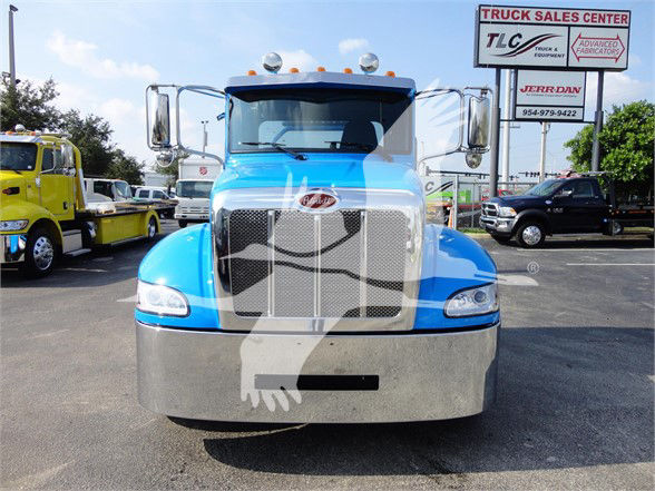 Peterbilt 337 truck front view showing large chrome grille and blue cab in dealership lot.