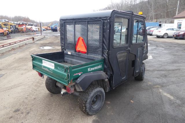 2011 Kawasaki KAF950G Utility Vehicle with cargo bed and mesh rear gate, black enclosed cab, off-road tires, used in a truck yard.