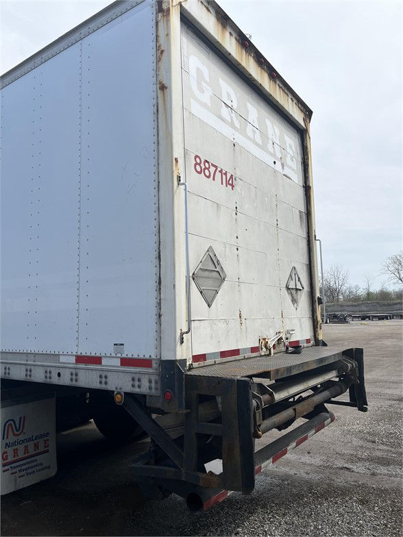 Rear view of a 2004 Wabash dry van trailer with gray doors, red stock number 887114, diamond hazard placards, and rear underride guard.
