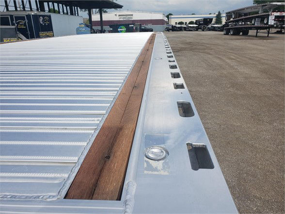 All-aluminum Fontaine Revolution 52 flatbed trailer edge showing tie-down points and wooden deck ridge along silver beam.