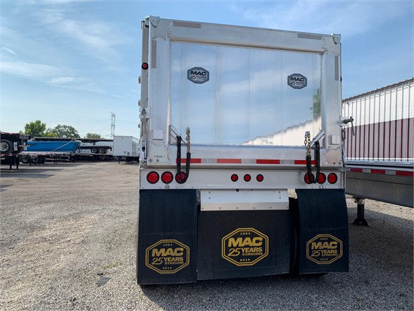 Rear view of a 24ft aluminum dump trailer with top hinge doors, MAC 25 Years logos on mud flaps, stock number 058948, flatbed area, reflective tape, and tail lights.