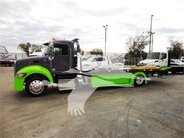 Peterbilt 337 tow truck with black cab and bright green lower body, long green-and-black chassis, front grille and wheels visible.