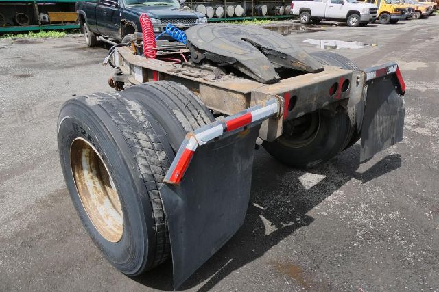 Trailer dolly showing rear wheel area with dual tires and mud flaps, red and blue air hoses, and metal frame.