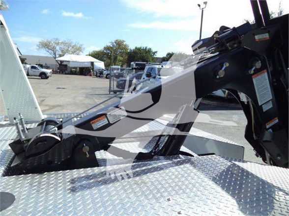 Ram 4500 tow truck chassis with hydraulic arm and control levers, diamond plate platform, warning stickers visible.