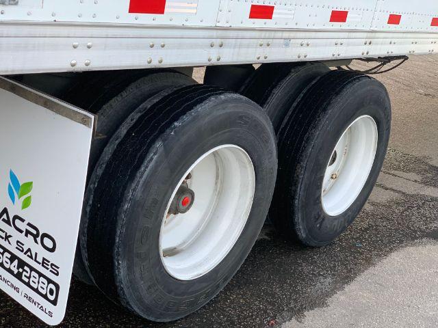 Stoughton dry van trailer wheels and tandem axles with black tires and white rims.