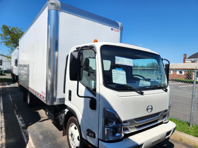 Box truck with white cab and large aluminum cargo box. Front grille and headlights visible. Side mirrors. Small windshield notes on the driver side.