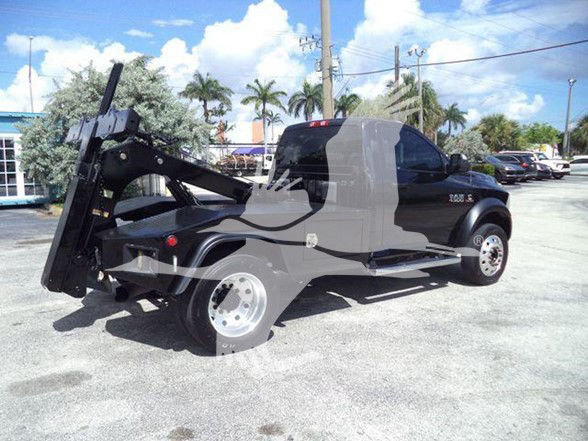 Ram 4500 pickup with a tow hoist in a dealership lot. Side view showing rear wheel and hoist mechanism.