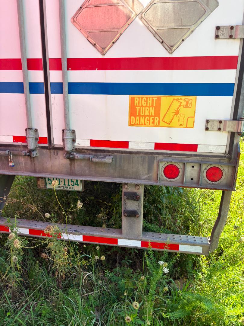 Rear view of a 2016 International Prostar truck with left door and bumper visible, showing hazard stickers and tail lights.