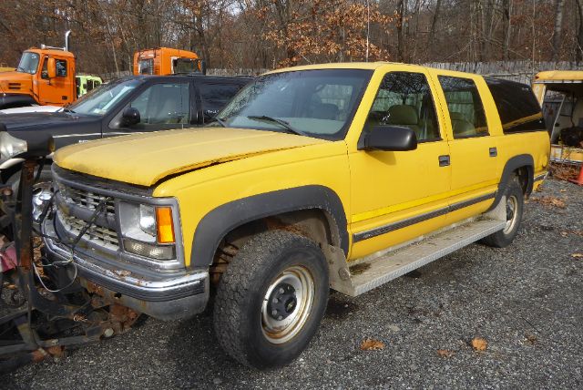 1999 Chevrolet Suburban front passenger side showing yellow body, black trim, and damaged front bumper.
