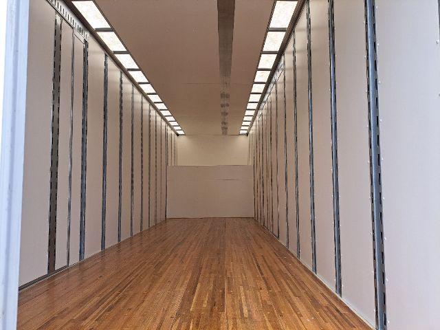 Truck trailer interior showing empty storage area with wooden floor and vertical metal support rails along both walls.