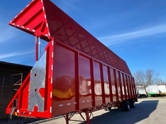 Transcraft 48 ft dump-style trailer in red, side panels extended, metal diamond plate at front, dual rear wheels, clear blue sky.