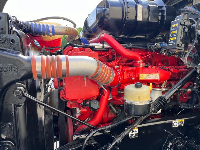 Truck engine bay of a 2014 Kenworth T800 with red engine, large orange intake hose, yellow coolant reservoir, and battery/air intake visible.