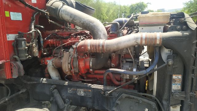 Engine bay of a Peterbilt 386 with red engine block, large intake/ exhaust piping, and radiator visible on right.