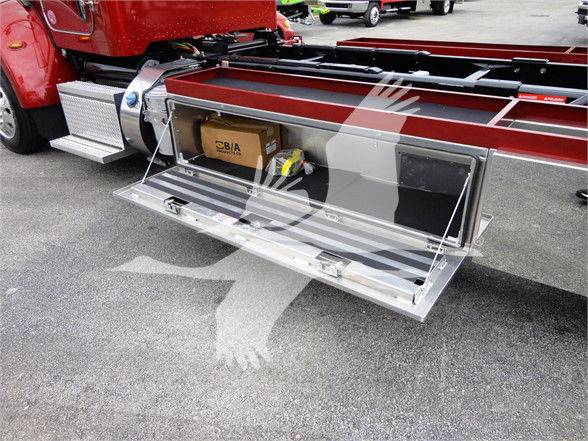 Peterbilt 337 truck side storage compartment open with metal diamond plate step and storage box visible.