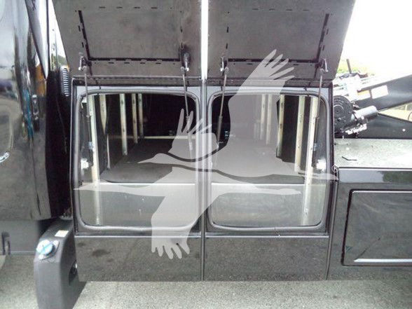 Two large rectangular compartments with hinged doors open, showing interior rails and storage area. Partial vehicle body panels and a step below.
