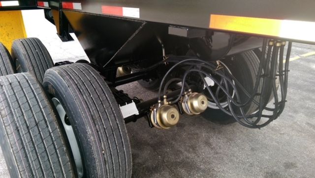 Dual circle air coupling and hydraulic lines under a dump trailer with tandem axles.
