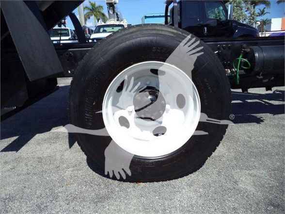 Truck wheel and part of chassis visible; white wheel rim with black tire. No legible labels or fluids visible.