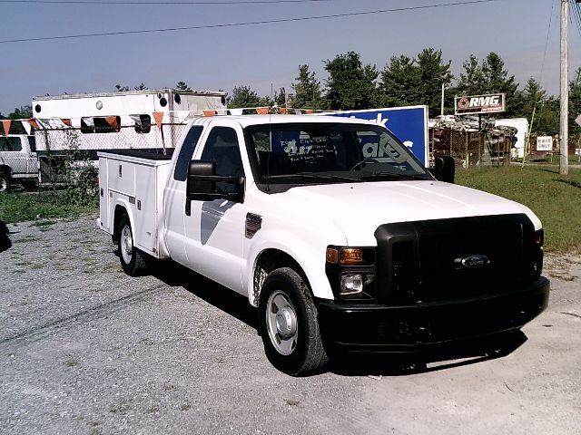 White Ford F-250 Super Duty utility truck with service body, front grille, headlights, black bumper, and utility compartments on the sides.