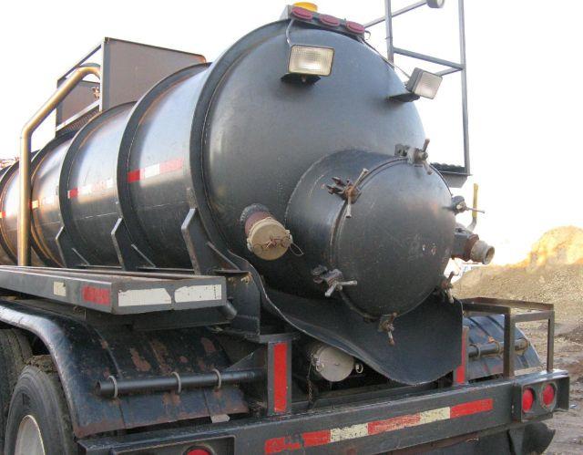 Harmon vacuum tanker trailer rear view showing circular tank with manhole and discharge fittings.