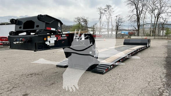 Truck trailer in a parking lot showing a flatbed deck with a drop system and a gooseneck, XL Specialized Mini Deck branding visible on the structure.