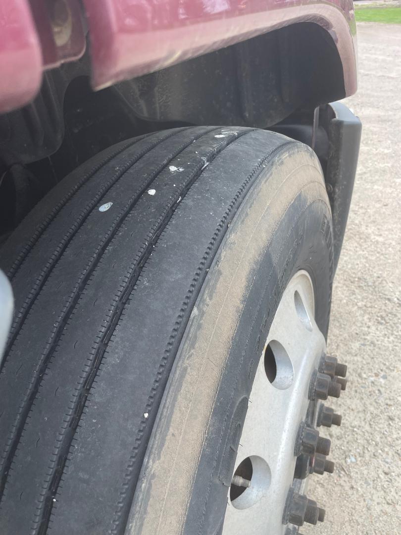 Truck wheel close-up showing front tire and steel rim with lug nuts on a Freightliner Cascadia 125.