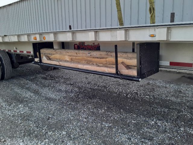 Trailer undercarriage showing a Dunnage Rack with lumber secured inside; black steel rack with coiled spring and mounting brackets.