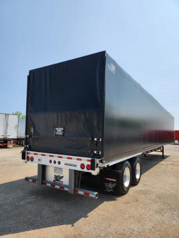 Trailer rear view of a 2020 Manac combo flatbed with a tall black tarp-covered cargo area, dual rear axles, and bumper with lights. Stock number 2023717.
