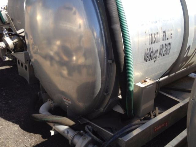 Vacuum tank trailer side showing cylindrical tank with hoses and mounting frame.