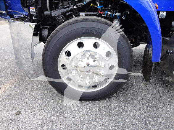 Front wheel of a 2022 Peterbilt 337 truck showing large steel wheel with multi-hole pattern and tire; partial blue fender and chassis components visible.