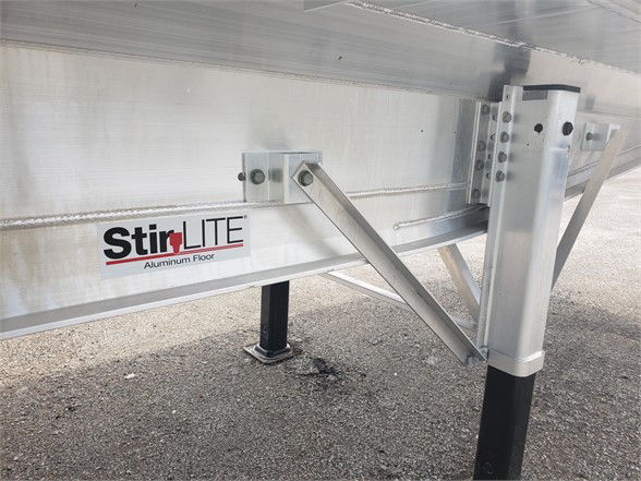 StirLite aluminum floor label on trailer frame showing logo and support brackets with a vertical leg and bolt holes.