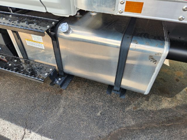Aluminum fuel tank strapped under a 2025 Hino L6 cab and chassis with side steps and visible chassis components.