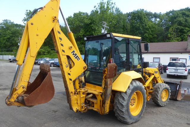 Massey Ferguson 50HX backhoe loader in yellow with front bucket and hydraulic arm, cabin windows visible.