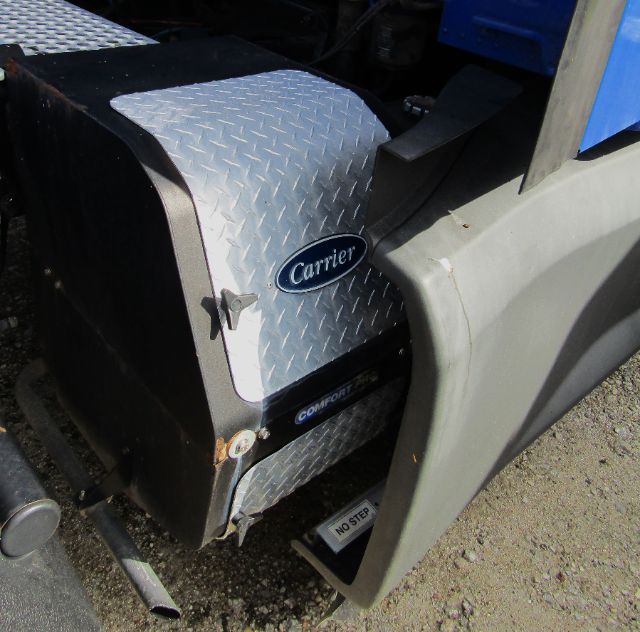 Close-up of a Kenworth Carrier badge on a diamond plate toolbox with fender and side panel; visible text includes Carrier and Comfort brand markings.