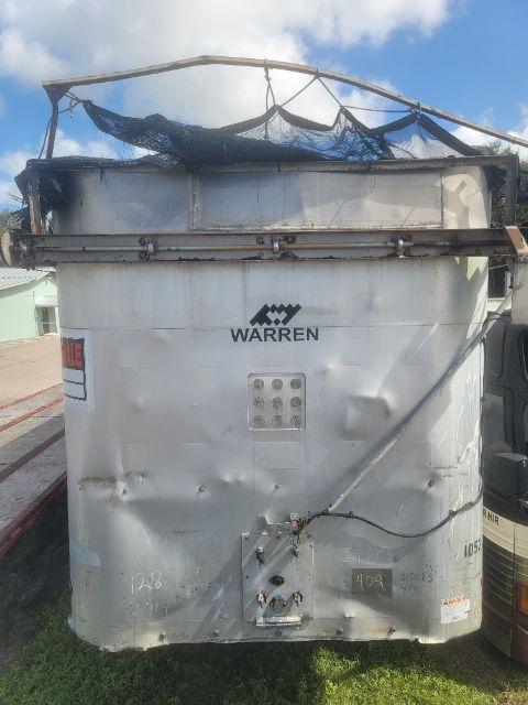 Rear view of a Warren WHDT48x102-2-AS walking floor trailer, silver body, with damaged tarp on top and Warren logo visible.
