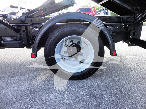 {Wheel well and spare tire on a 2023 Chevrolet Silverado 5500HD chassis; visible steel frame, wheel with black tire, red reflectors, and white rim.}