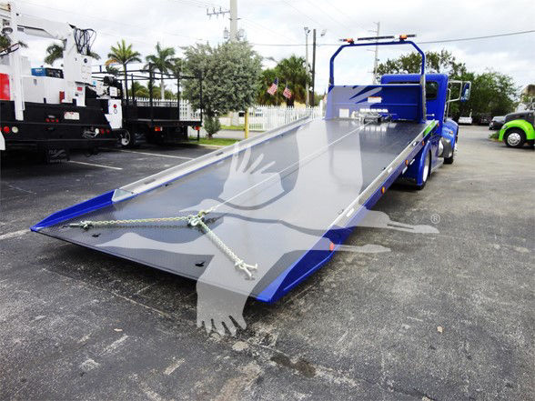 Tow truck with a blue flatbed ramp in a dealership lot,Peterbilt 337 chassis visible